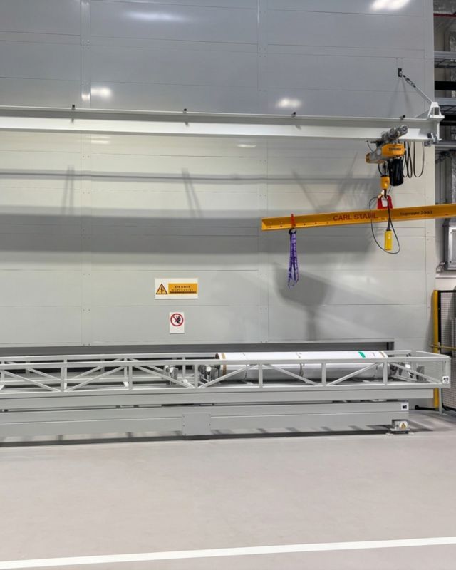 Instalație Turn LS complet închisă, cu sistem de macara integrat pentru încărcarea și descărcarea materialelor cilindrice grele într-un mediu de producție